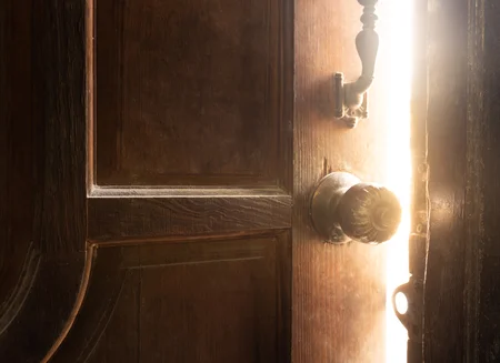 Puerta entreabierta misteriosa, con luz desde adentro.